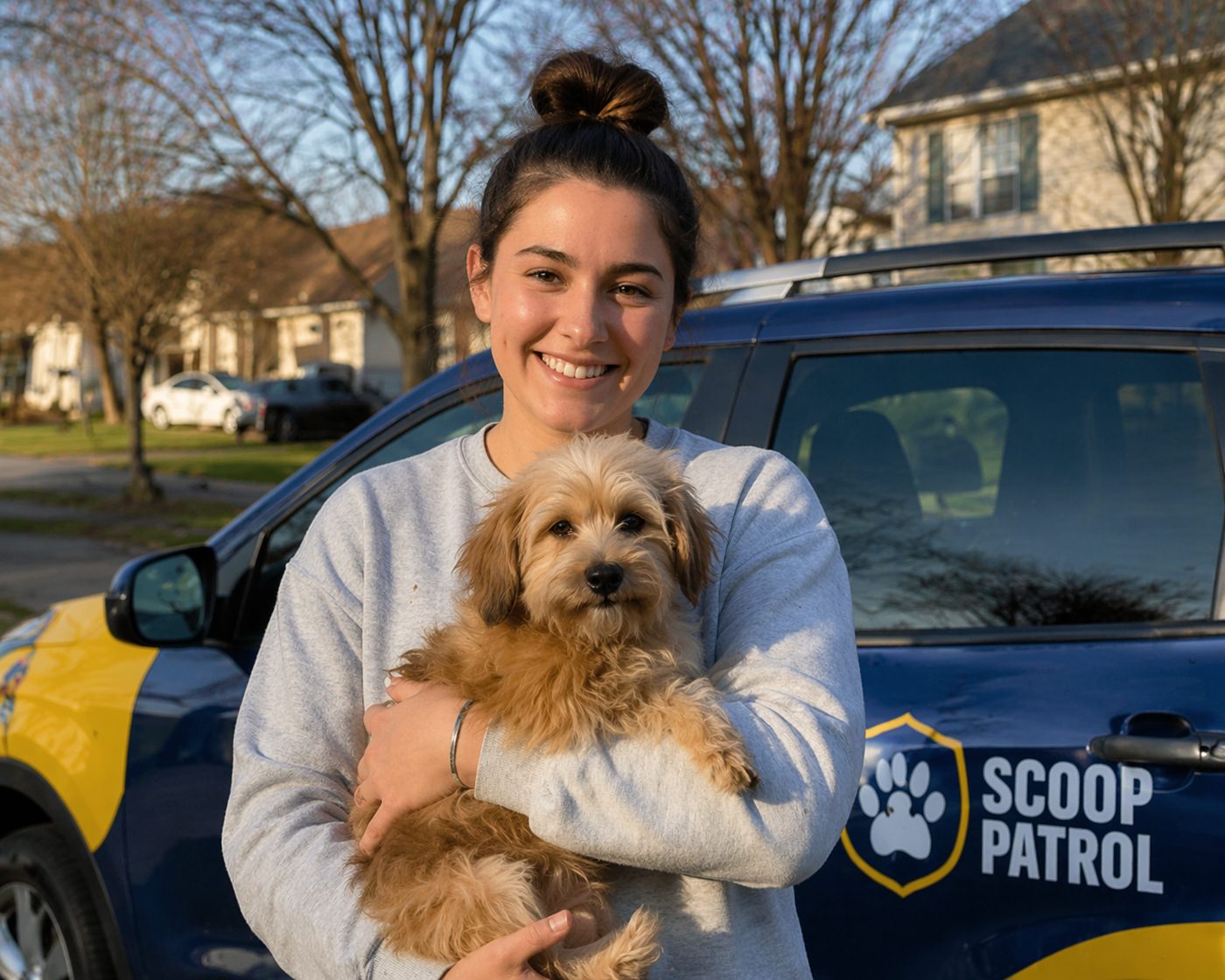 Dog owner with puppy beside a Scoop Patrol vehicle